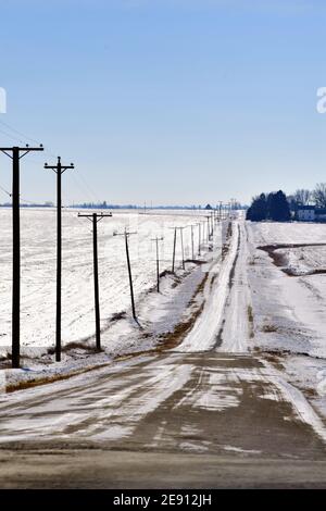 Cortland, Illinois, USA. Eine einsame Straße, die nur von Telefonumfragen begleitet wird, die sich mitten im Winter des Mittleren Westens bis zum Horizont erstrecken. Stockfoto