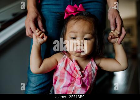 Pouting asiatische Kleinkind mit rosa Schleife im Haar lernen Gehen Stockfoto