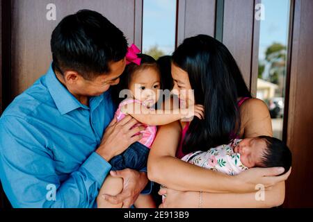 Asiatische Mutter halten neugeborenen lächelt bei Tochter gehalten von Papa Stockfoto