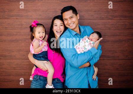 Glückliche asiatisch-amerikanische Familie mit Kleinkind Mädchen und schlafen Neugeborenen Stockfoto
