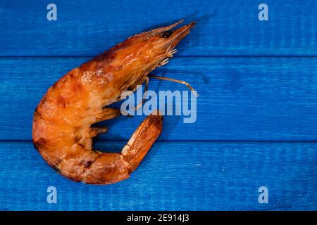 Nahaufnahme einer ganzen Garnele auf dem Grill auf einem hellblauen Brett gekocht. Hausmannskost, Stockfoto