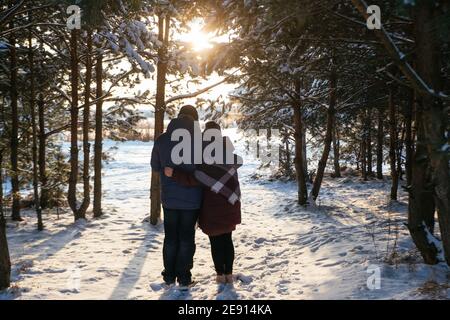 Paar stehen im Winterwald Blick auf den Sonnenuntergang in der Nähe Die gefrorenen Stockfoto