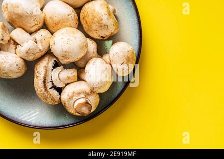 Draufsicht auf Teller mit weißen Champignon-Pilzen Gelber Hintergrund Stockfoto