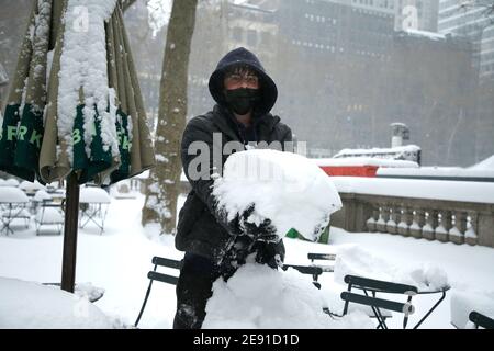 Ein Mann nimmt einen Schneehaufen im Bryant Park auf.die erste Nor'easter 2021 hat Gebiete der nördlichen und zentralen Ostküste einschließlich New York City mit über einem Fuß Schnee gepummelt. Die öffentlichen Verkehrsmittel sind in kürzerer Zeit in Betrieb und die Impfstellen für Coronaviren wurden eingestellt, was möglicherweise der größte Sturmflut seit dem Supersturm Sandy im Jahr 2012 ist. Stockfoto