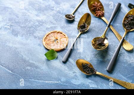 Löffel mit trockenen schwarzen Teeblättern auf farbigem Hintergrund Stockfoto