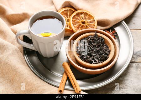 Tasse schwarzer Tee, trockene Blätter und Gewürze auf Holzgrund Stockfoto