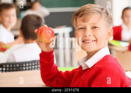 Schuljunge mit Apfel im Klassenzimmer Stockfoto