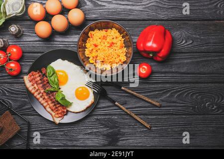 Teller mit leckeren Eiern und Schüssel mit Reis auf Holz Hintergrund Stockfoto