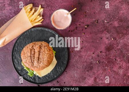 Tablett mit leckeren Burger, pommes Frites und Milchshake auf farbigem Hintergrund Stockfoto