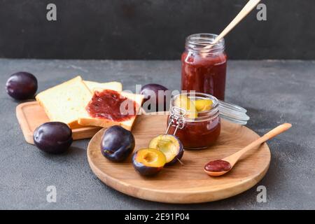 Komposition mit köstlicher hausgemachter Pflaumenmarmelade auf dunklem Hintergrund Stockfoto