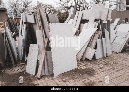 Im Hof einer Steinmetzwerkstatt gibt es viele Verschiedene Granit- und Marmorplatten stehen am Rand daneben Einander Stockfoto