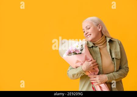 Reife Frau mit Blumenstrauß auf farbigem Hintergrund Stockfoto