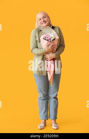 Reife Frau mit Blumenstrauß auf farbigem Hintergrund Stockfoto