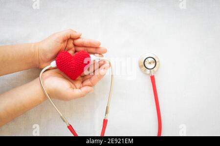Hand hält rotes Herz und Stethoskop auf weißem isolierten Hintergrund. Konzept für medizinische Herzgesundheit, Kardiologie, Versicherungsplan, Organspende, Doc Stockfoto
