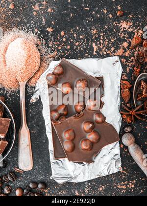 Schokolade mit Nüssen und Gewürzen in den Löffeln auf einem Dunkler Tisch Stockfoto