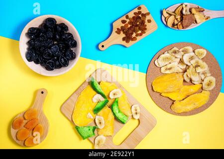 Mischung aus getrockneten Früchten auf TU Bischvat Mandala blau, gelber Hintergrund flach legen. Mango, Rosinen, Papaya, Bananen, getrocknete Aprikosen Stockfoto