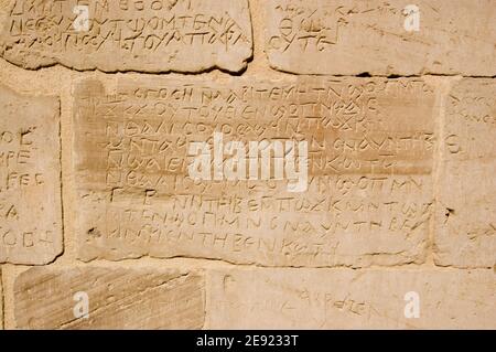 Alte griechische Schrift in die Wand eines alten ägyptischen Tempels in Deir el Medina, Luxor, Ägypten geschnitzt. Stockfoto
