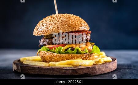 Köstlicher Burger mit Fleisch und Käse auf Holzplatte Stockfoto