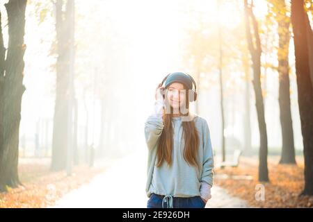 Nettes Mädchen, das Musik in Kopfhörern im Park hört Stockfoto