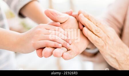 Verflechtung von jungen und alten Händen auf hellem Hintergrund Stockfoto