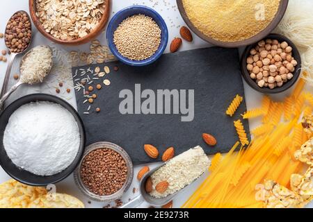 Glutenfreies Lebensmittelkonzept zeigt die Vielfalt der Produkte - Pasta, Mehl, Snacks, Hülsenfrüchte und Getreide - mit einem leeren schwarzen Schiefertafel für Ihren Text Stockfoto