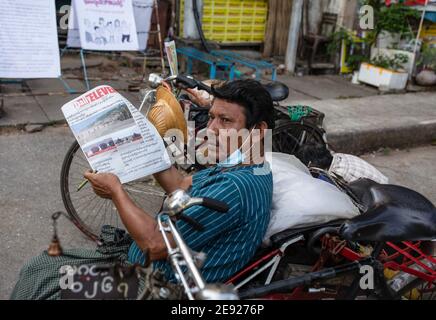 Yangon, Myanmar. Februar 2021. Ein Rikscha-Fahrer sah eine Zeitung lesen einen Tag, nachdem das Militär Myanmars de facto Führer des Landes Aung San Suu Kyi und der Präsident des Landes in einem Putsch festgenommen. Kredit: SOPA Images Limited/Alamy Live Nachrichten Stockfoto