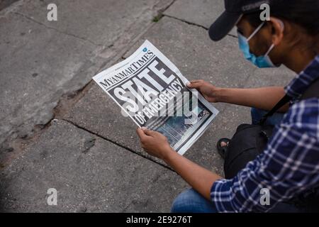 Yangon, Myanmar. Februar 2021. Ein Mann, der eine Gesichtsmaske trug, sah eine Zeitung der Myanmar Times lesen, mit der Überschrift "Notstand" einen Tag, nachdem das Militär Myanmars de facto Führer Aung San Suu Kyi und den Präsidenten des Landes in einem Putsch festgenommen hatte. Kredit: SOPA Images Limited/Alamy Live Nachrichten Stockfoto