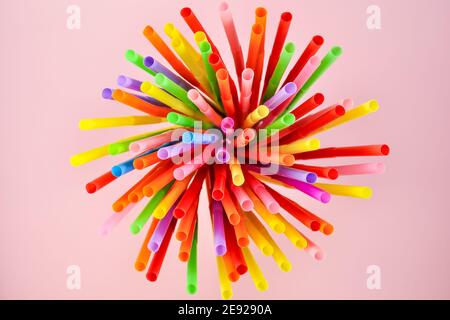 Draufsicht auf bunte Cocktail-Plastikstrohhalme auf rosa Hintergrund. Stockfoto