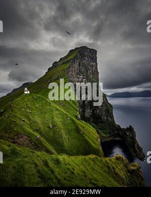 Blick auf die steilen Klippen und das Weiß und Rot Lichthaus von Kallur auf der Insel Kalsoy at Färöer-Inseln Stockfoto