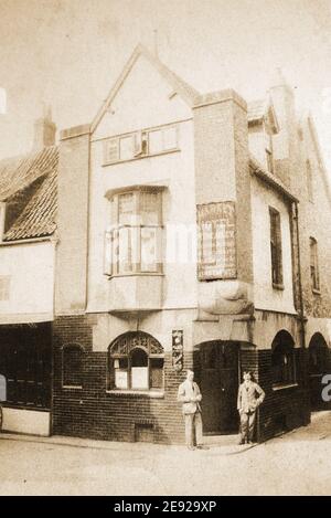 Das ehemalige Market Hotel im Market Place um 1925 am Ende von Sandgate, Whitby, North Yorkshire, einer der vielen Whitby Pubs, die aus der Stadt verschwunden sind. Es war früher bekannt als der Vogel in der Hand und umgangssprachlich knonw als einfach der Markt. Eine sehr dunkle Kneipe mit vielen Fächern, die 1904 fast geschlossen wurde, weil sie innen 'aufgeschlagen' wurde und kein Urinal hatte. Der Vermieter außerhalb der Kneipe abgebildet sein kann Walter Brearly, war dort von 1923-c1932. In seinen letzten Tagen hatte das beliebte Pub seine Wände mit Royal Navy Matrosen Kappen gespendet von lokalen & Besuch Segler gesäumt. Stockfoto