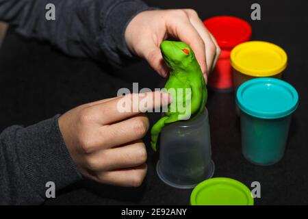 Selektive Fokus der Hand des Kindes versuchen, einen Frosch mit bunten Spiel Teig zu schaffen, für die Aktivität der Kinder. Schule, Kindergarten oder Kindergarten Unterricht Kunststoff Stockfoto