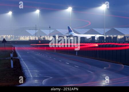 02. Februar 2021, Sachsen, Schkeuditz: Autos fahren über das Gelände des Flughafens Leipzig/Halle. (Long Exposure Shot) der Flughafen entwickelt sich weiterhin zu einem der wichtigsten Drehkreuze für Luftfracht in Europa. Obwohl die Passagierzahlen vor allem aufgrund der Corona-Pandemie zurückgingen, stieg der Frachtdurchsatz deutlich: 2020 stieg er um 11.7 Prozent auf knapp 1.4 Millionen Tonnen. Allein im Dezember stieg die Luftfracht um 35 Prozent. Dank einer speziellen Zertifizierung können auch empfindliche pharmazeutische Produkte am Flughafen gehandhabt werden, was somit eine wichtige Rolle spielen könnte Stockfoto