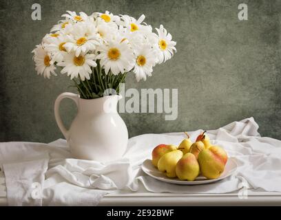 Stillleben mit Blumenstrauß in einem Glas Und frische Birnen auf Holztisch Stockfoto