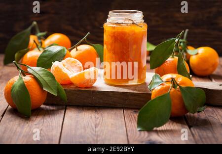Glas von Mandarinenmarmelade mit frischen Früchten auf Holz Tabelle Stockfoto