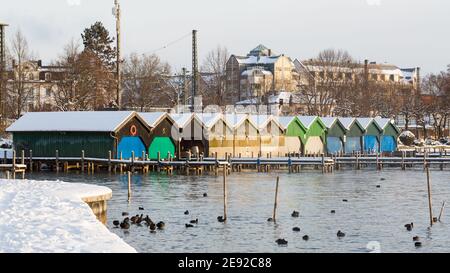 Starnberg, Deutschland - 19. Jan 2021: Bunte, hölzerne Bootshäuser während der Wintersaison. Am Starnberger See. Stockfoto