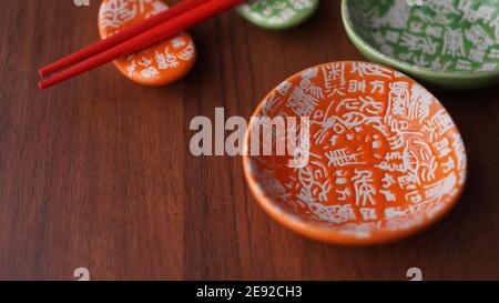 Set aus Keramikgeschirr für Sushi und rote Sushi-Sticks Auf Holzhintergrund Stockfoto