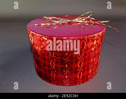 Runde und rote geschlossene Geschenkbox isoliert auf grauem Hintergrund Für besondere Anlässe Stockfoto