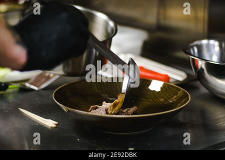 Küchenchef bereitet Ramen-Nudelsuppe mit Fleisch, Eiern und Gemüse in einem Restaurant zu Stockfoto