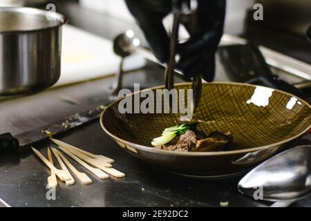 Küchenchef bereitet Ramen-Nudelsuppe mit Fleisch, Eiern und Gemüse in einem Restaurant zu Stockfoto