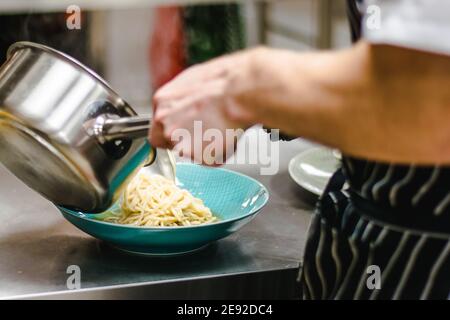 Küchenchef bereitet Ramen-Nudelsuppe mit Fleisch, Eiern und Gemüse in einem Restaurant zu Stockfoto