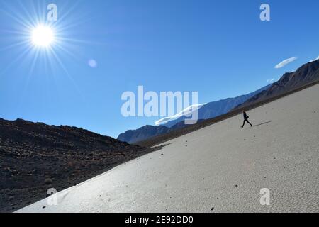 Frau, die an einem kalten Dezembertag über die Rennstrecke Playa im Death Valley National Park spazierengeht, wunderschöne Landschaft mit sich bewegenden Felsen, die Spuren hinterlassen Stockfoto