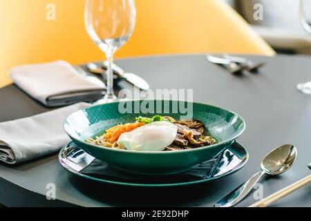 Rinderramen-Suppe mit pochiertem Ei und Gemüse bei a Restaurant Stockfoto