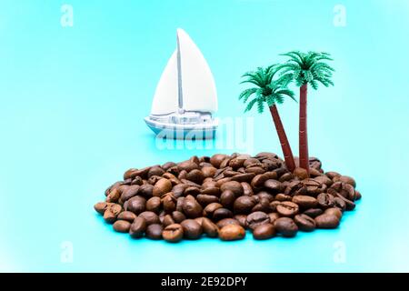 Kreative Illusion einer abgelegenen Insel im Meer aus gerösteten Kaffeebohnen, Plastikpalmen und einem Spielzeug-Segelboot auf hellblauem Hintergrund Imita Stockfoto