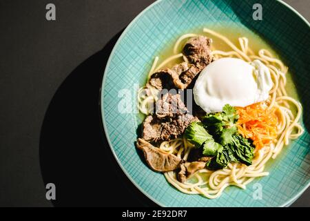 Rinderramen-Suppe mit pochiertem Ei und Gemüse bei a Restaurant Stockfoto