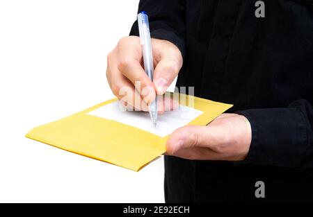Der Mann in schwarzer Uniform schreibt eine Adresse auf ein Gelb gepolsterter Umschlag isoliert auf weiß Stockfoto