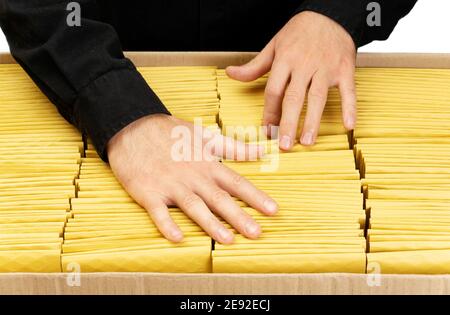 Mann in schwarzer Uniform Zählung gelb gepolsterte Blase Umschläge in einem großen Karton. Stockfoto