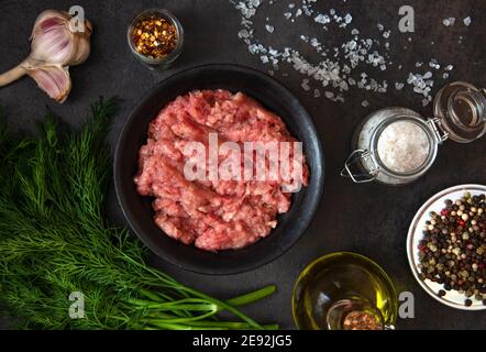 Hausgemachtes Hackfleisch in einer schwarzen Schüssel mit Zutaten. Frisches, rohes Hackfleisch. Draufsicht. Stockfoto