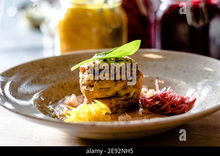 Hecht-Cutlet mit Kürbissauce und fermentierten Kohl in verschiedenen Farben in einem Restaurant Stockfoto