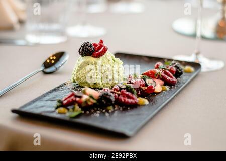 Eis auf einem schwarzen Teller mit Früchten und Sauce In einem Restaurant Stockfoto