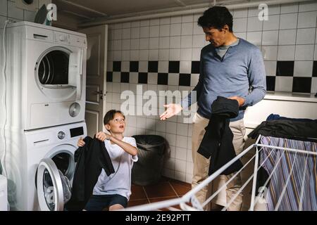 Sohn und Vater erledigen Aufgaben im Hauswirtschaftsraum Stockfoto